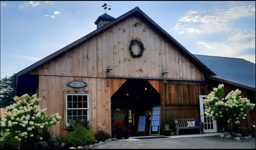 Rustic wooden barn entrance decorated with a wreath and signs.