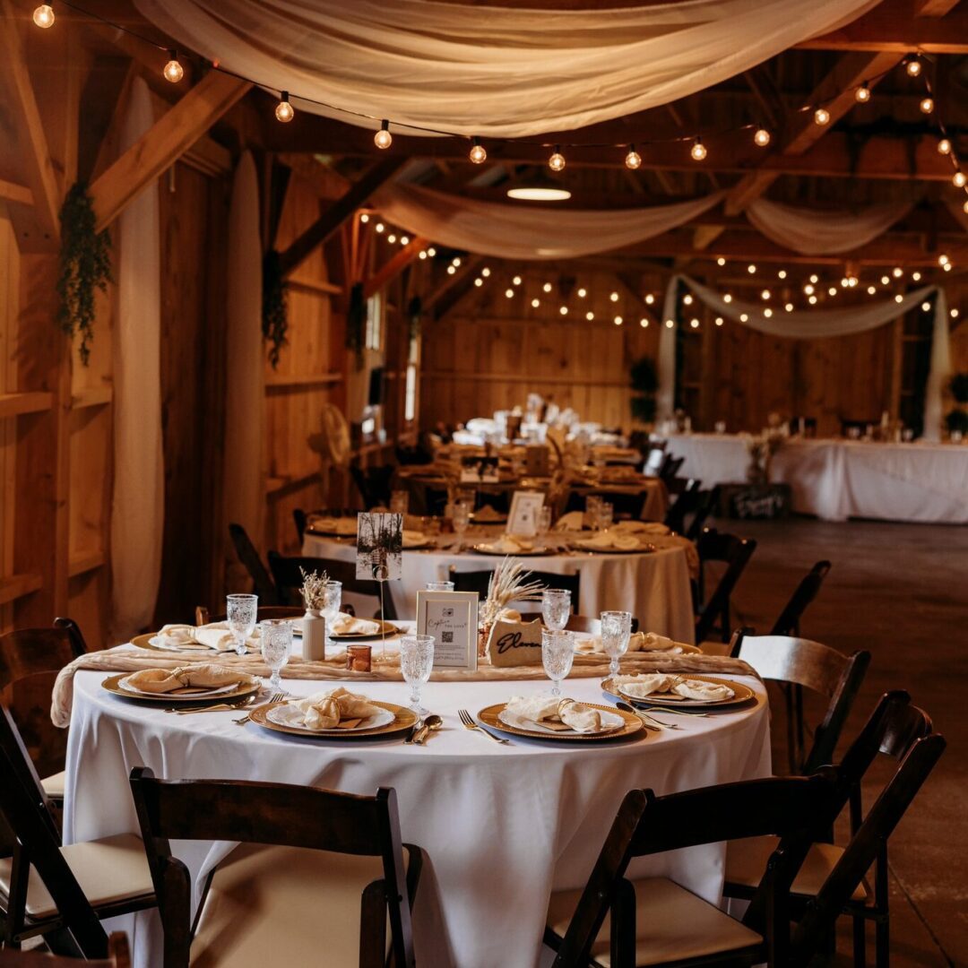 Elegant rustic wedding reception setup with string lights and round tables.