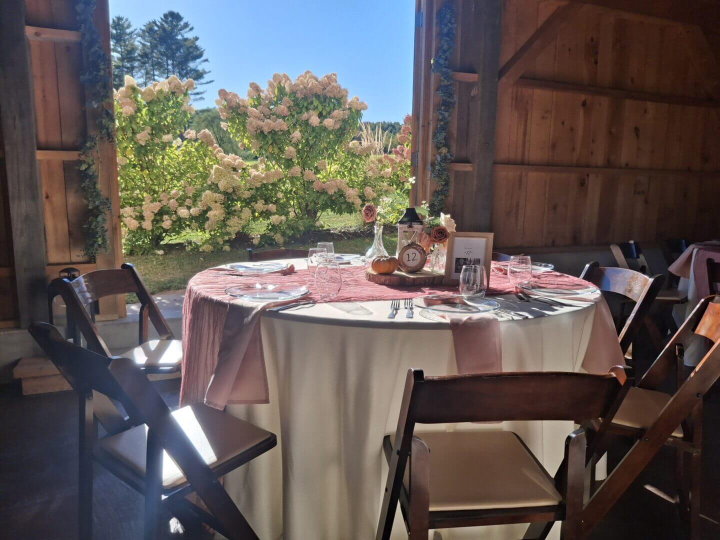 Elegant round table set for an outdoor meal with garden view.